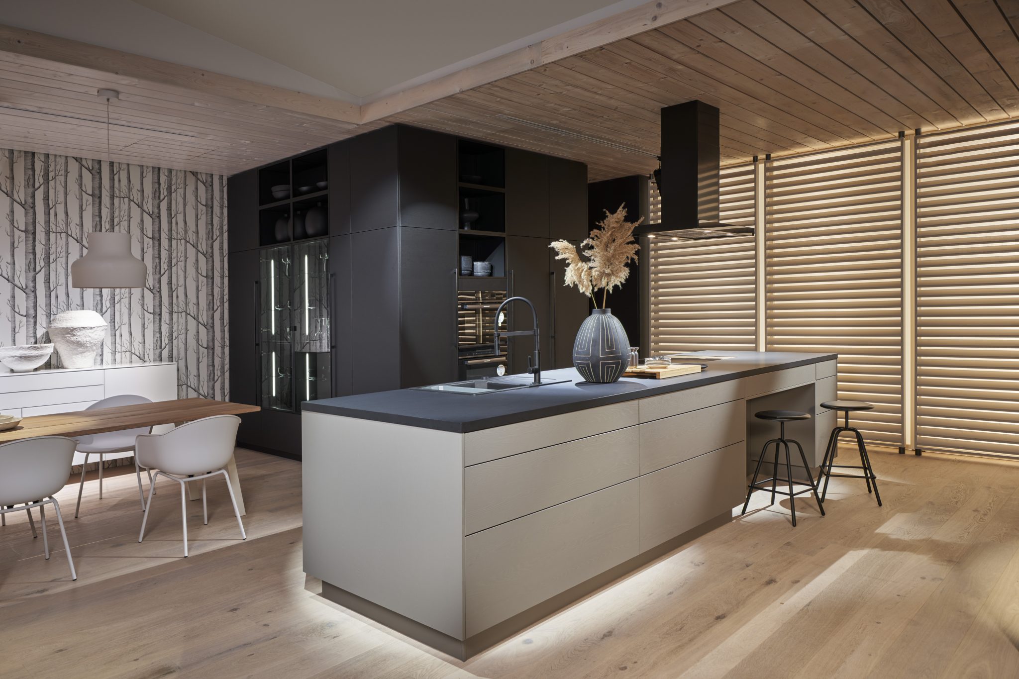 Graue Küche mit Kücheninsel und zusätzlichem Essbereich. 