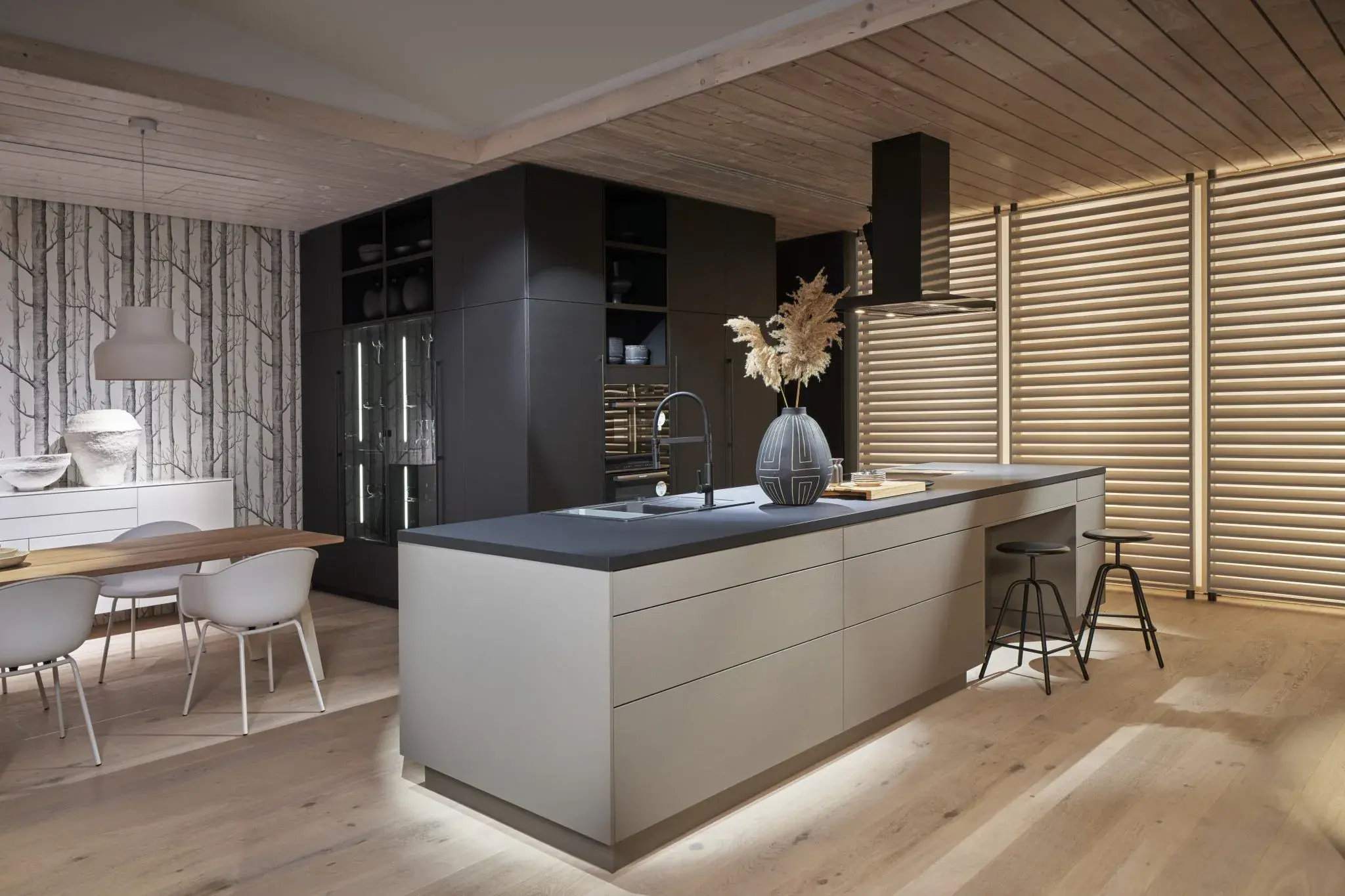 Graue Küche mit Kücheninsel und zusätzlichem Essbereich. 